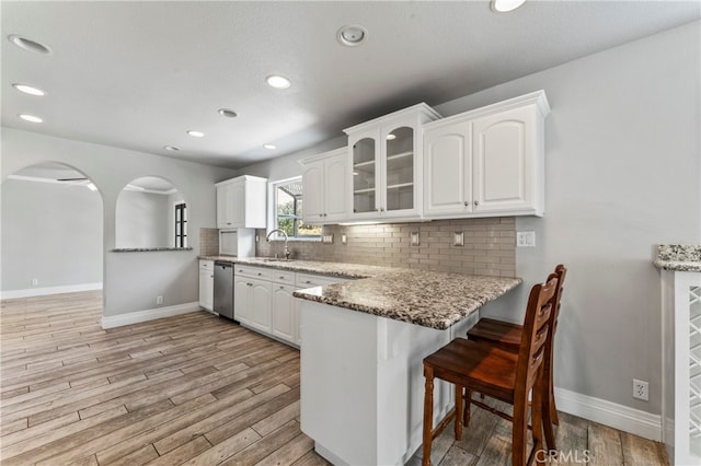 kitchen featuring light hardwood / wood-style flooring, white cabinets, light stone counters, and stainless steel dishwasher