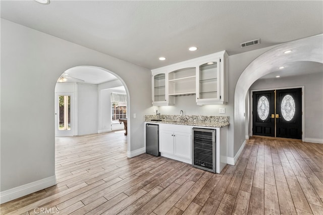 kitchen with beverage cooler, light hardwood / wood-style flooring, sink, and white cabinets