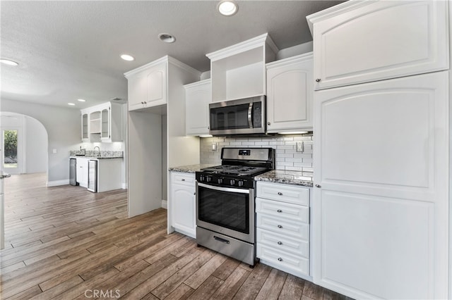 kitchen featuring white cabinets, appliances with stainless steel finishes, hardwood / wood-style floors, and stone countertops