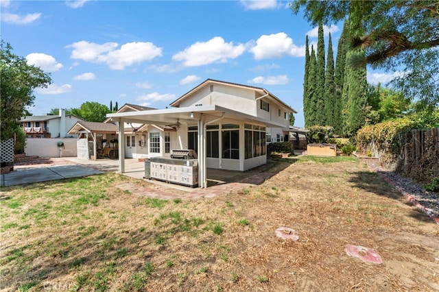 rear view of house featuring a lawn, ceiling fan, a sunroom, and a patio area