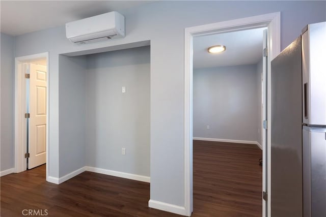 unfurnished bedroom featuring fridge, an AC wall unit, and dark hardwood / wood-style flooring