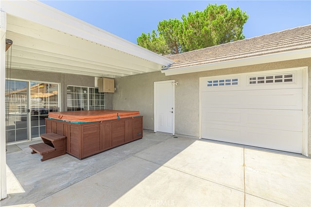 view of patio featuring a garage and a hot tub