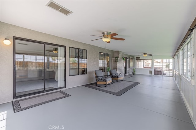 unfurnished sunroom featuring ceiling fan and plenty of natural light