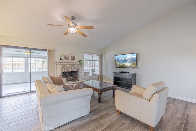 living room with ceiling fan, a fireplace, vaulted ceiling, and a healthy amount of sunlight