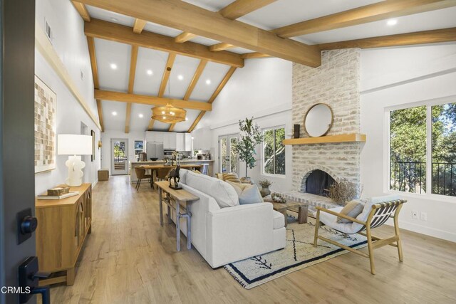 living room with light hardwood / wood-style flooring, high vaulted ceiling, beamed ceiling, and a brick fireplace