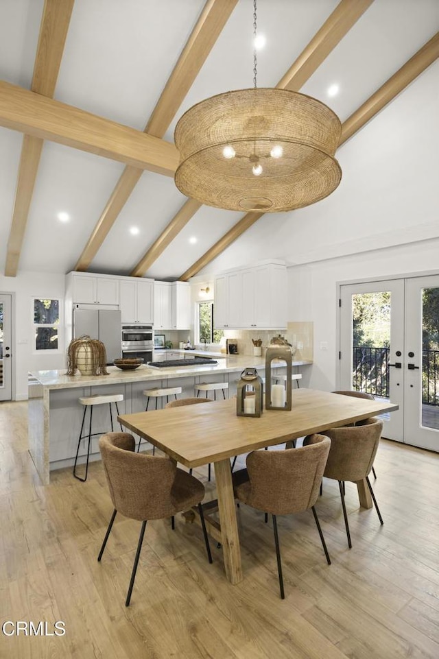 dining area featuring beamed ceiling, plenty of natural light, light hardwood / wood-style floors, and french doors