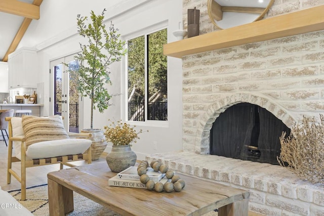 interior space with vaulted ceiling with beams, wood-type flooring, and a brick fireplace