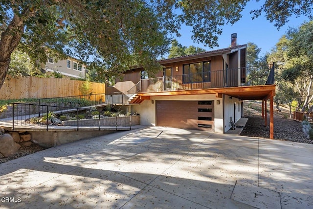 view of front of house with driveway, a chimney, an attached garage, and fence