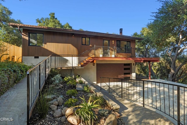 view of front of house featuring driveway, fence, and stairway