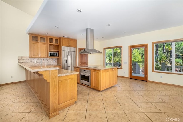 kitchen with island exhaust hood, built in appliances, kitchen peninsula, a kitchen bar, and backsplash