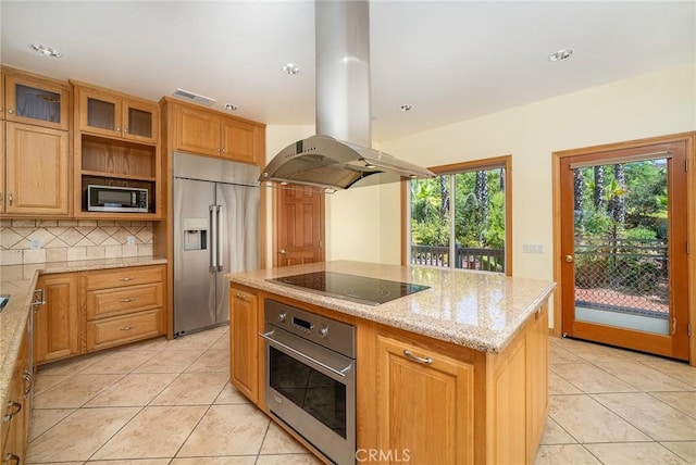 kitchen featuring island range hood, stainless steel appliances, light stone counters, a kitchen island, and tasteful backsplash