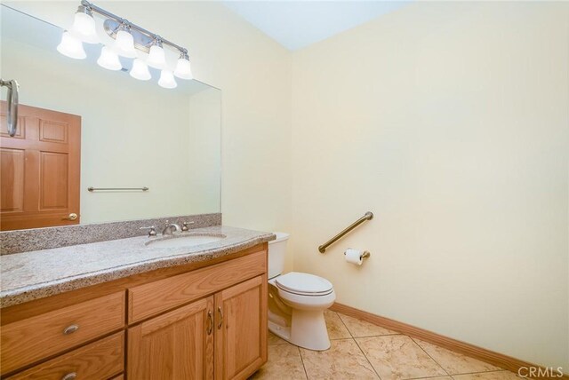 bathroom with toilet, tile patterned flooring, and vanity