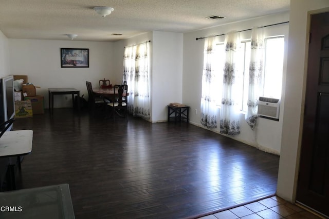 living room featuring cooling unit, dark wood-type flooring, and a textured ceiling