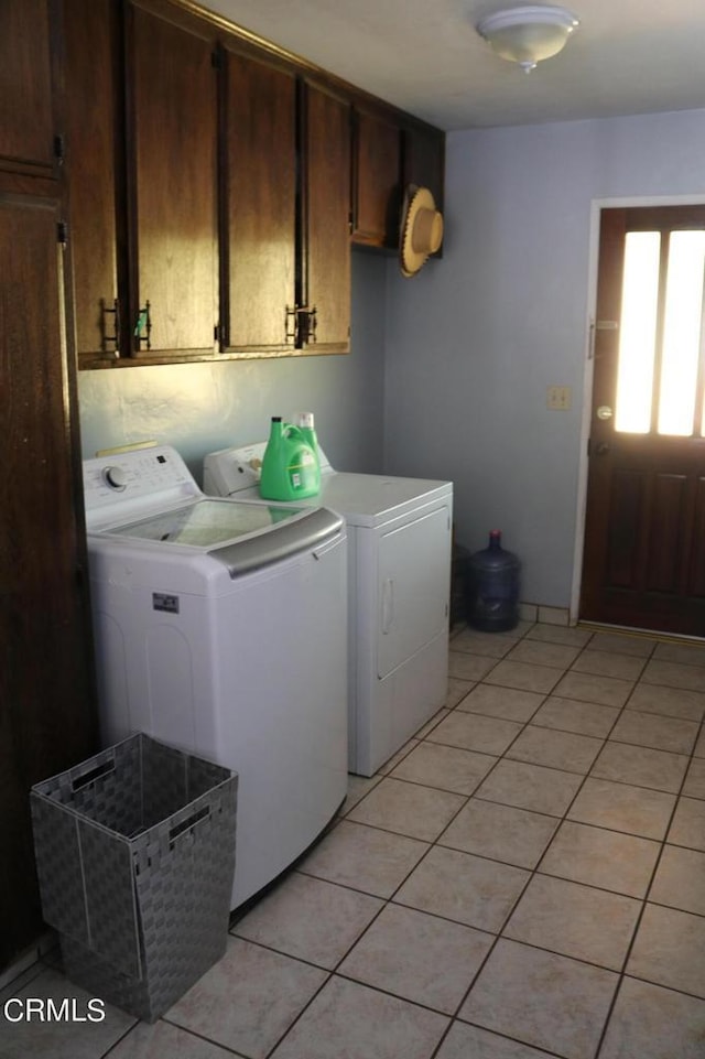 laundry room with washing machine and dryer, light tile patterned flooring, and cabinets