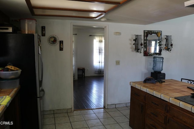 kitchen with stainless steel refrigerator, tile countertops, and light hardwood / wood-style floors