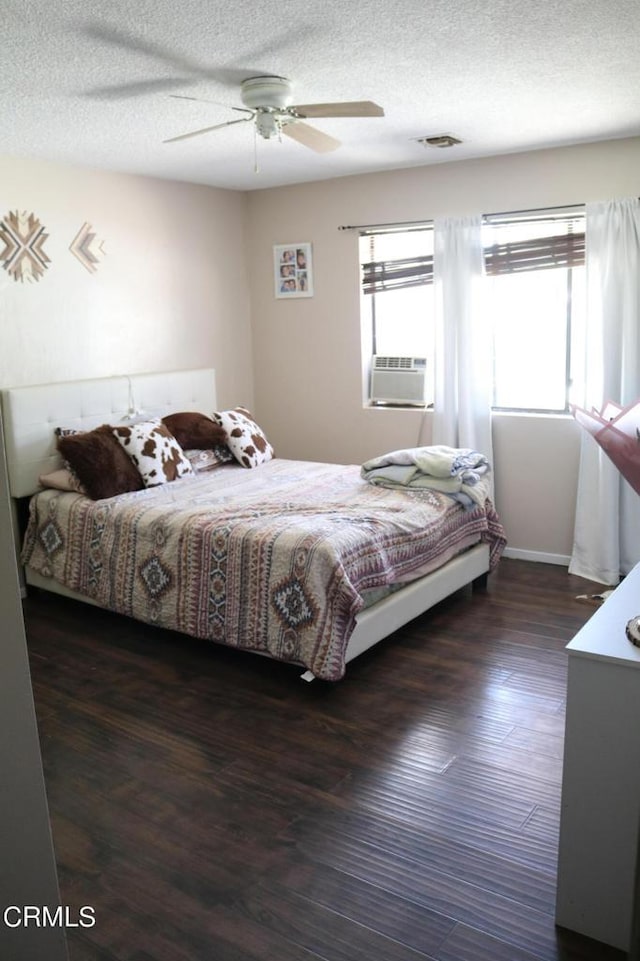 bedroom featuring ceiling fan, cooling unit, dark wood-type flooring, and a textured ceiling