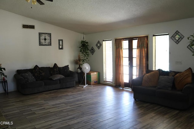 living room with a textured ceiling, ceiling fan, dark hardwood / wood-style flooring, and vaulted ceiling