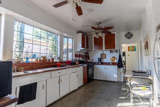 kitchen with sink, white cabinets, black range oven, crown molding, and ceiling fan