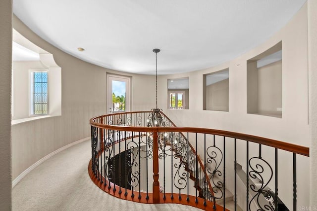 corridor featuring an inviting chandelier and carpet