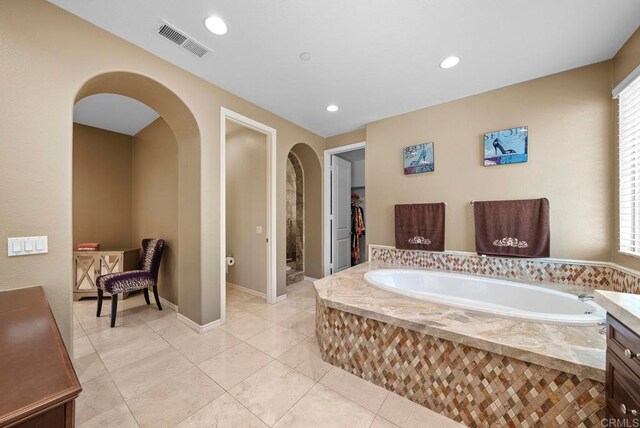 bathroom featuring vanity, tiled tub, and a healthy amount of sunlight