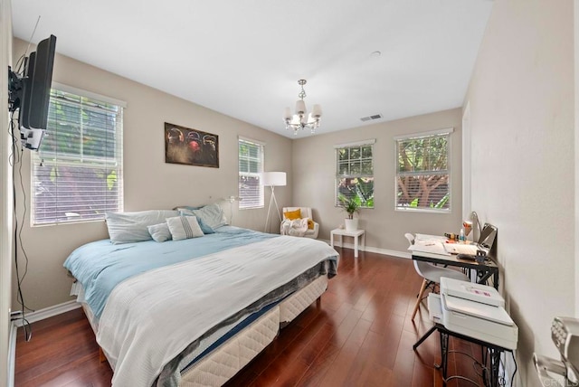 bedroom with dark hardwood / wood-style floors and a notable chandelier