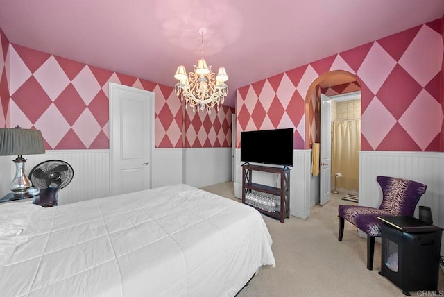 carpeted bedroom with connected bathroom and a chandelier