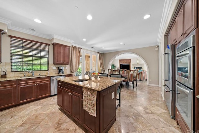 kitchen with appliances with stainless steel finishes, decorative backsplash, an island with sink, french doors, and ornamental molding