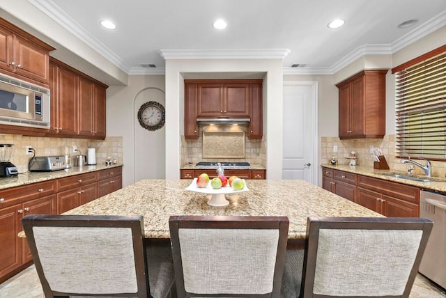 kitchen with a kitchen island, sink, stainless steel appliances, and light stone counters