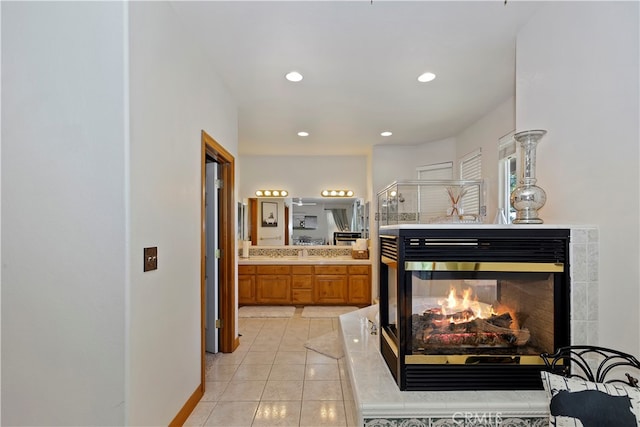 bathroom with vanity, tile patterned floors, a shower with shower door, and a multi sided fireplace