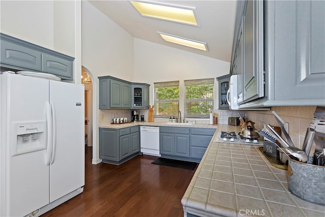 kitchen with dark wood-type flooring, tile counters, white appliances, and tasteful backsplash