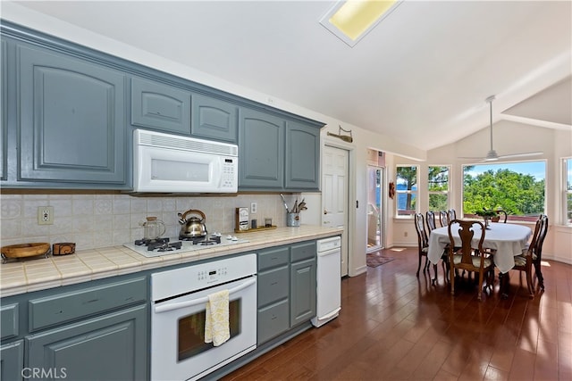 kitchen featuring lofted ceiling, tile countertops, dark hardwood / wood-style floors, decorative light fixtures, and white appliances