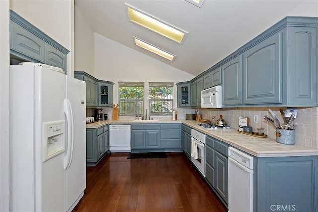 kitchen featuring white appliances, sink, backsplash, lofted ceiling, and dark hardwood / wood-style floors