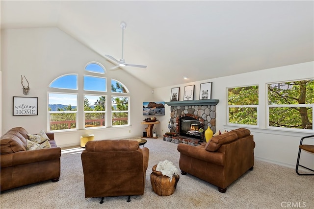 carpeted living room featuring a stone fireplace, high vaulted ceiling, and ceiling fan