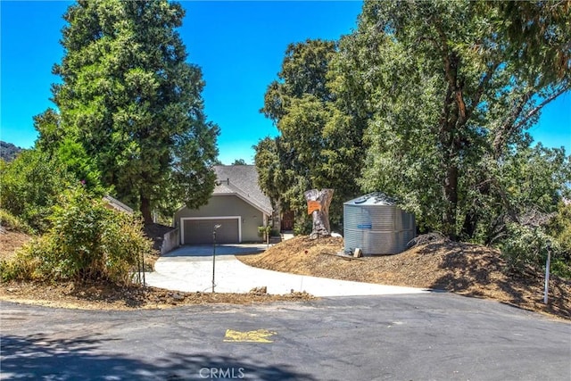 view of property hidden behind natural elements with a garage and driveway