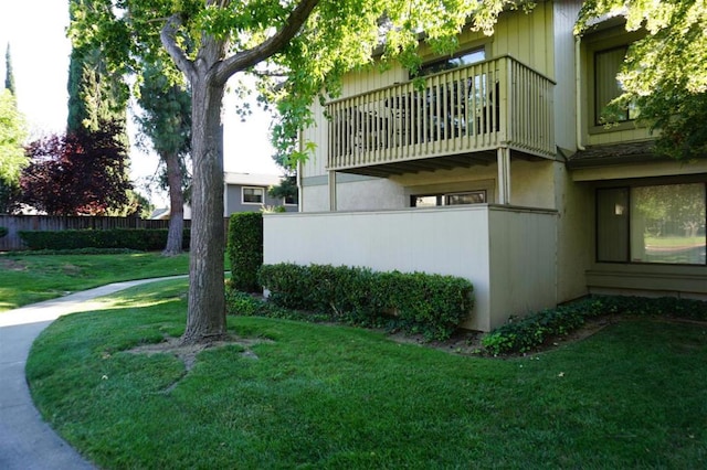 view of side of property with a balcony and a yard