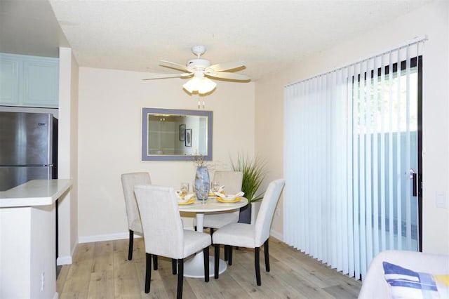 dining area with a textured ceiling, light hardwood / wood-style floors, and ceiling fan