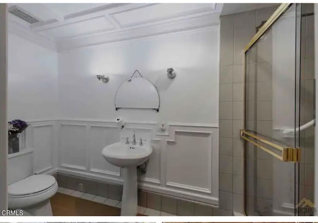 bathroom with toilet, tile patterned floors, and a shower with shower door