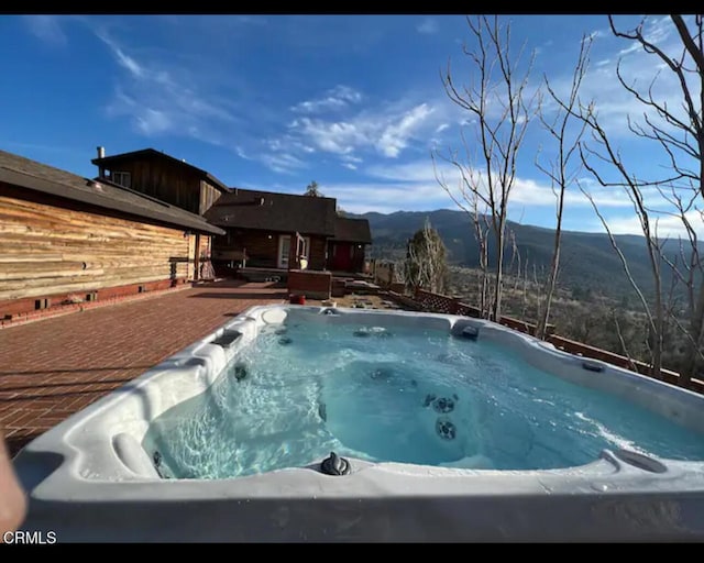 view of swimming pool with a mountain view and a hot tub