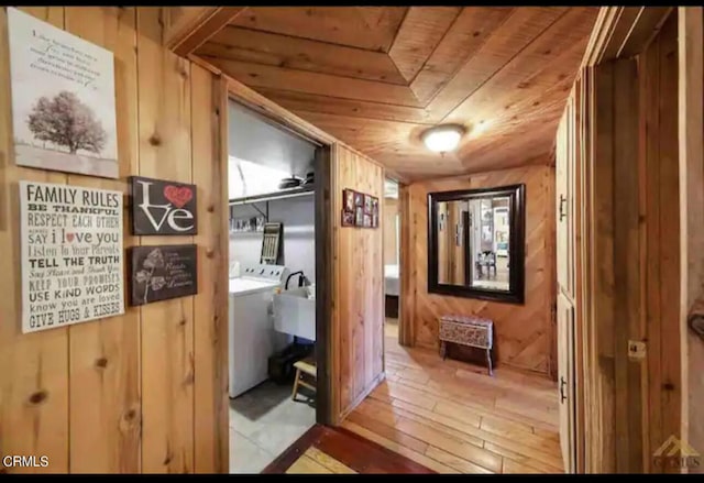 hall featuring light hardwood / wood-style flooring, washer / clothes dryer, wooden walls, and wooden ceiling