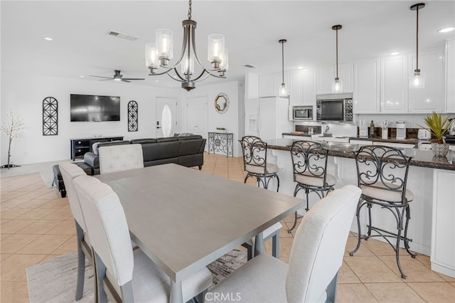 tiled dining area featuring ceiling fan with notable chandelier