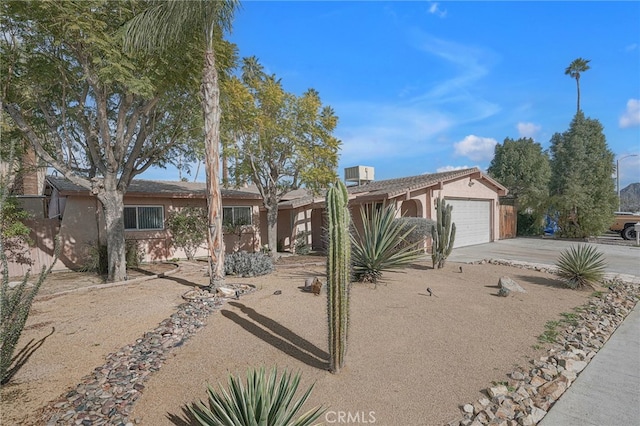 single story home featuring cooling unit and a garage