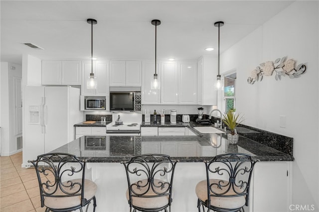 kitchen featuring dark stone counters, sink, white cabinets, hanging light fixtures, and white appliances