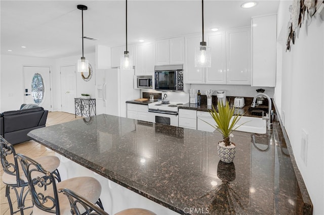 kitchen featuring dark stone counters, white appliances, white cabinetry, and decorative light fixtures