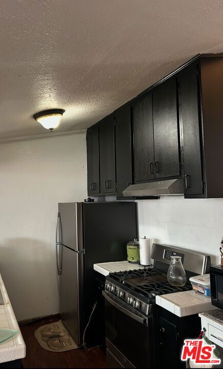 kitchen with tile countertops, gas range, and a textured ceiling