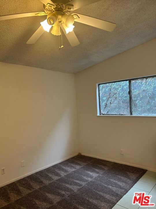 carpeted spare room featuring a textured ceiling and ceiling fan