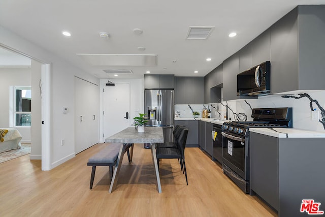 kitchen featuring gray cabinetry, light wood-type flooring, backsplash, and black appliances