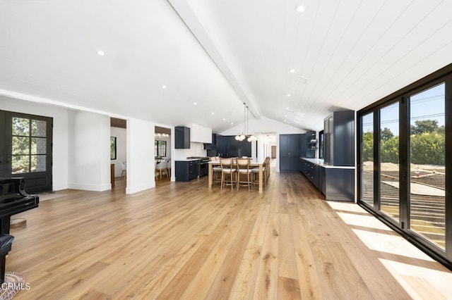 dining space with light hardwood / wood-style floors, lofted ceiling with beams, and an inviting chandelier