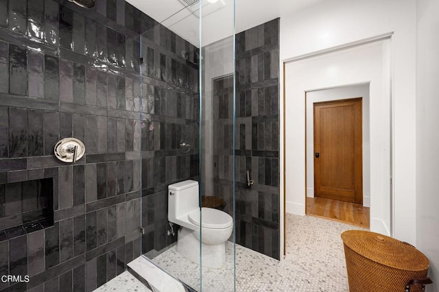 bathroom featuring wood-type flooring, a fireplace, a shower with shower door, and toilet