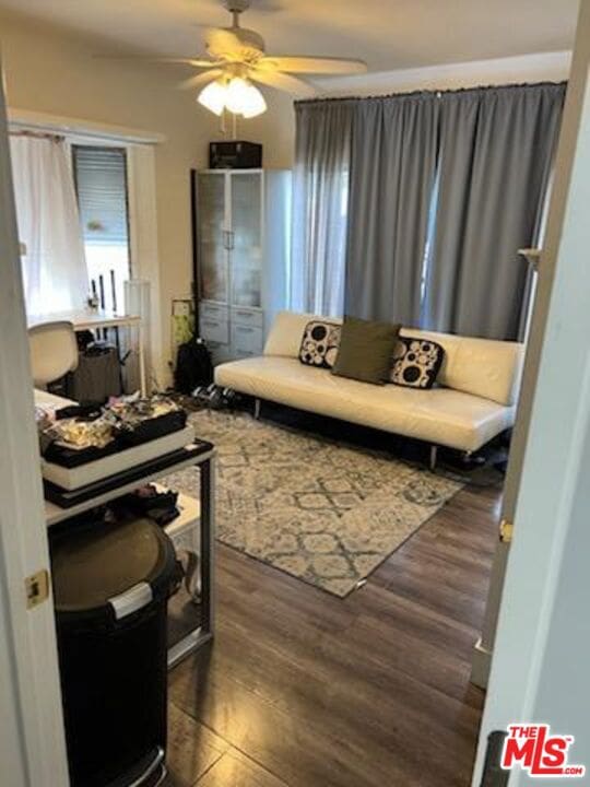 living area with ceiling fan and dark hardwood / wood-style flooring