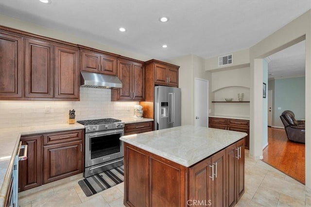 kitchen featuring light stone countertops, a center island, tasteful backsplash, high end appliances, and light tile patterned flooring